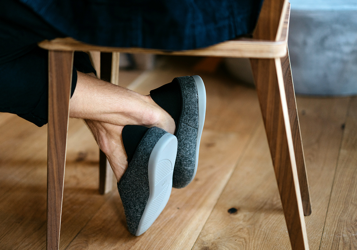 Ansicht eines hochwertigen Eichen-Massivholzdielenbodens und der Beine eines modernen Holzstuhls mit einer sitzenden Person.