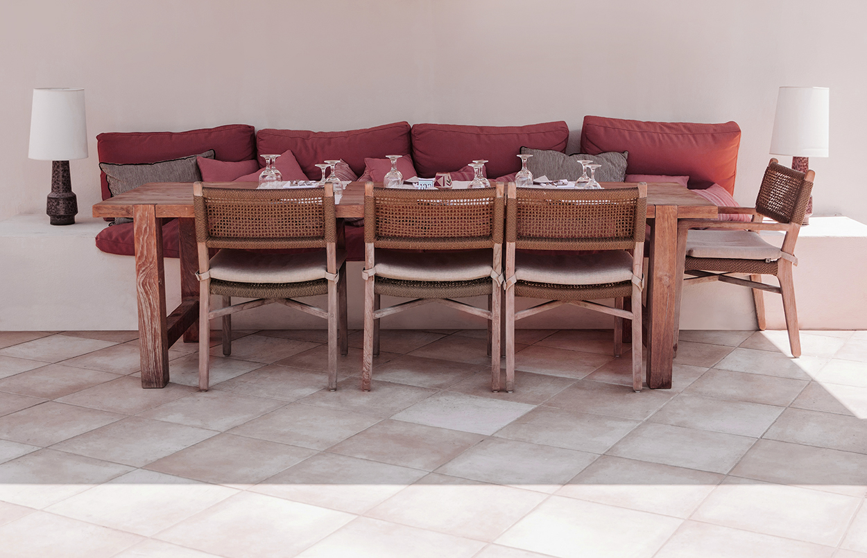 Helle Keramikfliesen auf Terrasse mit Holztisch.