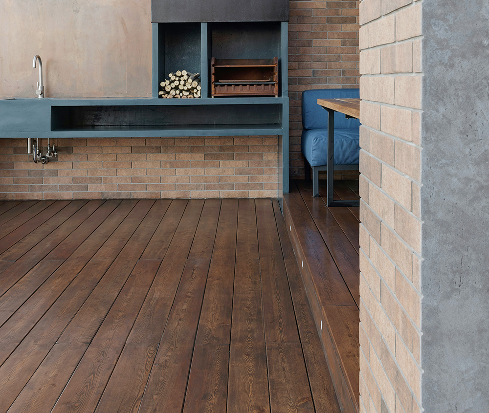 Dunkles Holzdeck und Steinwaschbecken vor Ziegelwand.